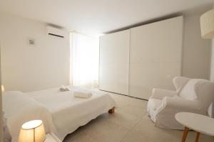 a white bedroom with a bed and a chair at Villa delle Muse in Marsala