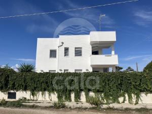 a white house with a sign in front of it at La Torre - Piano Primo By Cala Salento in Torre Lapillo