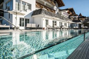 a swimming pool in front of a house at Berghotel Almrausch in Berwang
