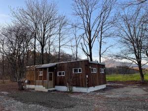 a small wooden building in a field with trees at sauna cota niseko サウナ付き一棟貸し in Kaributo