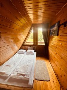 a bed in a wooden room with a window at Willa Koniora - sauna, balia, biliard in Międzybrodzie Bialskie