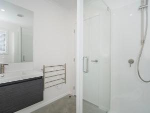 a white bathroom with a shower and a sink at Blue Skies - Whitianga Holiday Home in Whitianga +14 photos