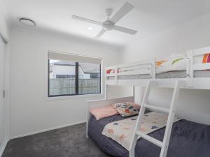 a bedroom with two bunk beds and a ceiling fan at Blue Skies - Whitianga Holiday Home in Whitianga