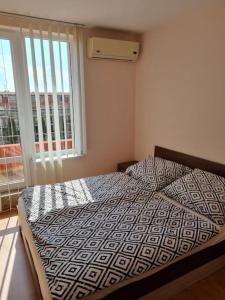 a bed in a bedroom with a large window at Sunny beach family apartment 302, Sluneční pobřeží in Sunny Beach