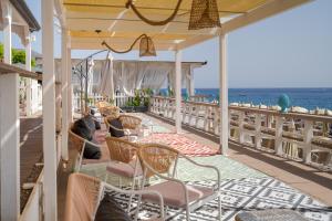 a patio with chairs and the ocean in the background at Hotel Rivage Taormina in Taormina