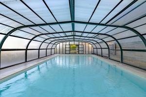 een overdekt zwembad met een glazen plafond bij Domaine la Noyeraie Périgord Noir in Paulin