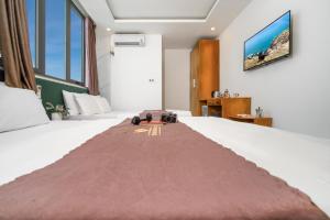 a hotel room with a bed with a blanket on it at Trang Ngan Hotel by THG in Danang