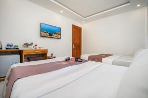 a hotel room with two beds and a desk at Trang Ngan Hotel by THG in Danang