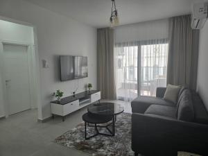 a living room with a couch and a tv at Aspasianus 1-Bedroom Pool View Apartment in Caesar Resort in Perivolia tou Trikomou