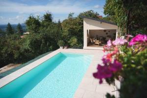 a swimming pool in front of a house with purple flowers at La Parenthèse, Les Gîtes de Montfaucon in Montfaucon +5 photos