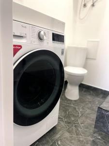 een wasmachine in een badkamer met toilet bij Uliha street sea side apartment in Liepāja