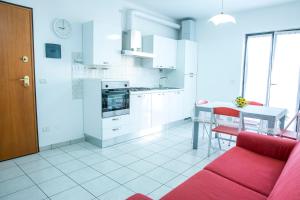a white kitchen with a red couch and a table at Ficus Pineto Vacanza in Pineto