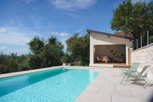 a swimming pool with chairs and a house at La Parenthèse, Les Gîtes de Montfaucon in Montfaucon