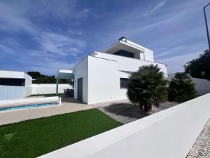 a white house with a white fence and a yard at Vila Alivia in Nadadouro