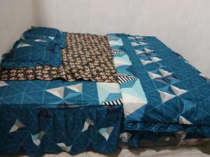 a bed with a blue quilt on top of it at Cena Homestay in Rejeng