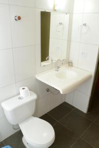 a white bathroom with a toilet and a sink at Requinte Hotel in Altamira
