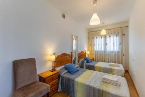 a bedroom with two beds and a chair at Casa Rural Arbana in Segovia