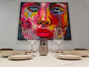 a table with wine glasses and a painting of a woman at Seascape 24 in Mellieħa