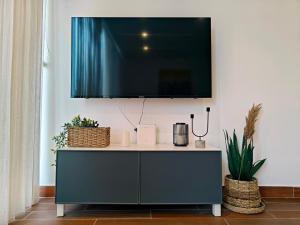 a tv on a white wall with a cabinet at Seascape 24 in Mellieħa