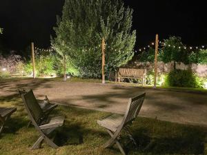two chairs and a bench in a park at night at La Corti in Tillières-sur-Avre +60 photos