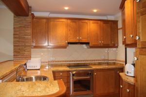 une cuisine avec des armoires en bois et un évier dans l'établissement Calpe Beachfront Apartment, à Ifach