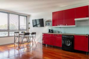 una cocina con armarios rojos y una mesa con sillas. en Bel appartement F2 42 m2, en Ivry-sur-Seine