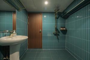 baño con lavabo y ducha con azulejos azules en Stay Passport Hongkong Goseong, en Goseong
