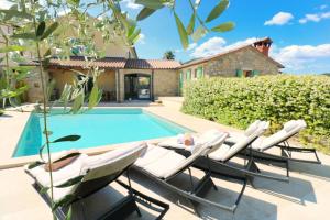 a group of lounge chairs next to a swimming pool at Villa Benvenuti near Motovun for 8 people - pet friendly with salt - water pool in Kaldir