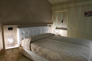 una camera con un grande letto con testiera bianca di Alessi Hotel Trattoria a Desenzano del Garda