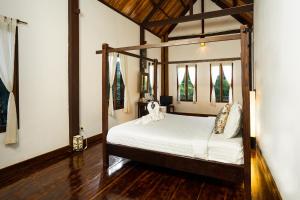 ein Schlafzimmer mit einem Himmelbett in einem Zimmer in der Unterkunft Villa Khoum Xieng Thong Boutique in Luang Prabang
