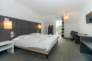 a bedroom with a large white bed and a desk at Résidence Goélia Le Domaine de Pont-Aven in Pont-Aven