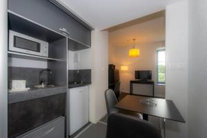 a small kitchen with a table and a microwave at Résidence Goélia Le Domaine de Pont-Aven in Pont-Aven +17 photos
