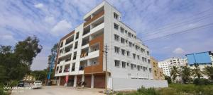 a tall white and brown building on a street at SGR Luxury Homes in Kammasandra