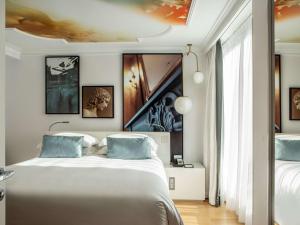 a bedroom with a large white bed with blue pillows at Sofitel Roma Villa Borghese in Rome