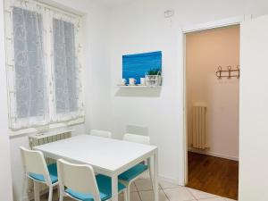 a white dining room with a white table and chairs at La finestra sul lago in Malgrate