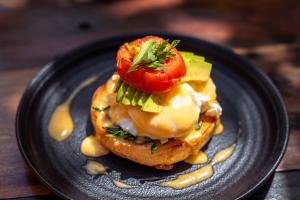 a black plate with a sandwich with a tomato on it at The Garten Living in Paje