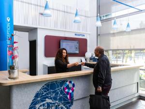 a man and a woman shaking hands at a counter at ibis budget Paris Porte de Vincennes in Paris