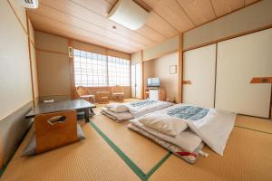 a room with two beds and a desk in it at くつろぎと料理の御宿花さと -Hanasato- in Minamiizu