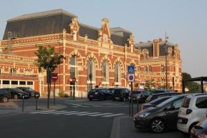 een groot bakstenen gebouw met auto's geparkeerd voor het bij L'appart T2 de la gare - Cambrai in Cambrai
