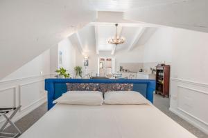 Un dormitorio con una cama azul en una habitación blanca. en Palazzo Desiderio, en Castellammare di Stabia