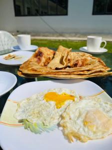 a table topped with plates of eggs and toast at Relax Cottages & Resort Kalam in Kalām