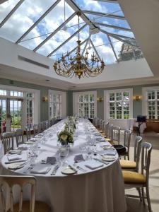a long table in a room with a chandelier at Willington Hall Hotel in Tarporley