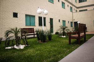 two benches in the grass in front of a building at Vera Cruz Business Hotel in Acailandia