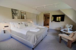 a large white bedroom with a large bed and a chair at Margretetorps Gästgifvaregård in Hjärnarp