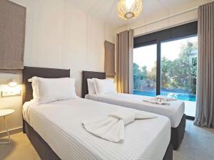 two beds in a hotel room with a window at Gaia by Vintage Travel in Ágios Dimítrios +26 photos