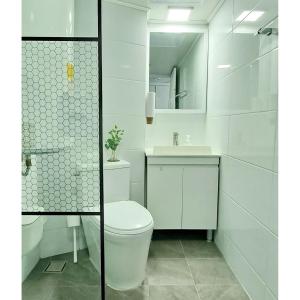 a white bathroom with a toilet and a sink at Stay Gangali with view of Gwangan bridge in Busan