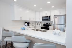 una cocina con armarios blancos, fregadero y electrodomésticos en Pelicans Roost 305 condo, en Sanibel