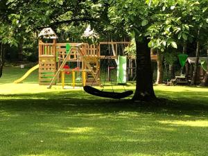 a playground with a hammock and a tree in a park at La Chouette BY OUT & LODGE in Couvin