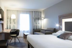 Habitación de hotel con cama blanca y escritorio en Novotel Château de Versailles, en Versalles