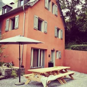 a picnic table with an umbrella in front of a building at ESTRELIAS - maison de vacances - Cauterets centre in Cauterets